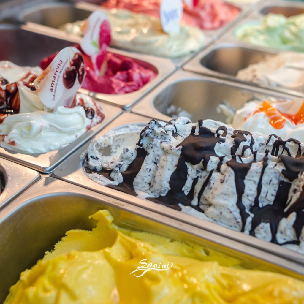 Gelato artigianale esposto in vaschette in acciaio con gusti assortiti