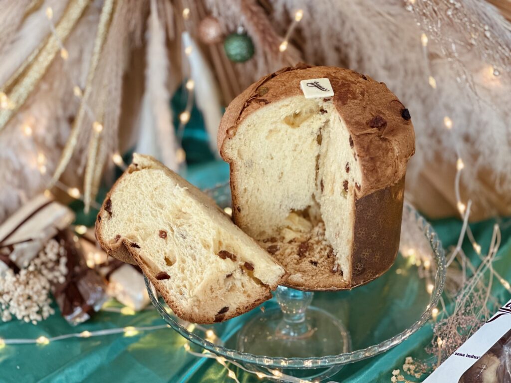 Panettone artigianale classico con uvetta, su alzata decorativa natalizia, Pasticceria Savini.