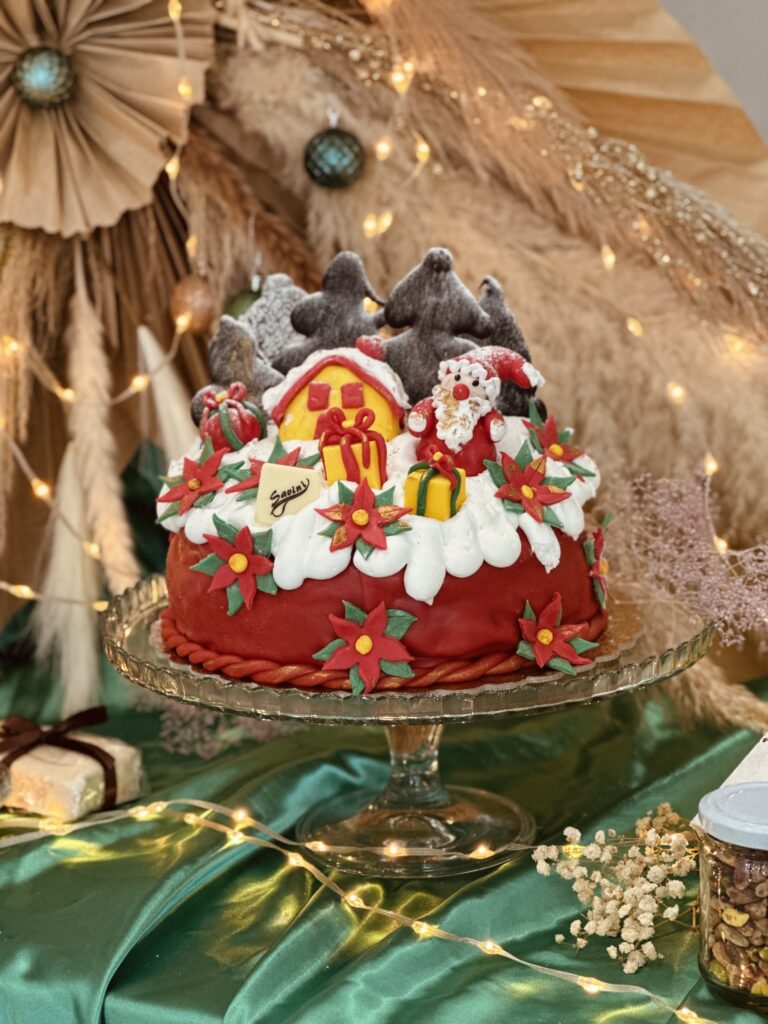 Panettone artigianale Savini decorato a tema natalizio con pasta di zucchero, casetta, Babbo Natale, pacchi regalo, stelle di Natale e alberelli innevati.