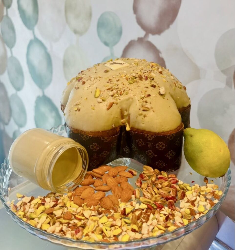 Dolce artigianale natalizio a forma di stella ricoperto di glassa al pistacchio, decorato con granella di mandorle, pistacchi e limone, accompagnato da crema spalmabile.